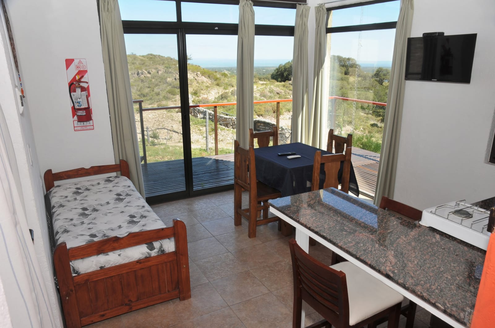 Interior de una cabaña con comedor, kitchenette y vista a la sierra
